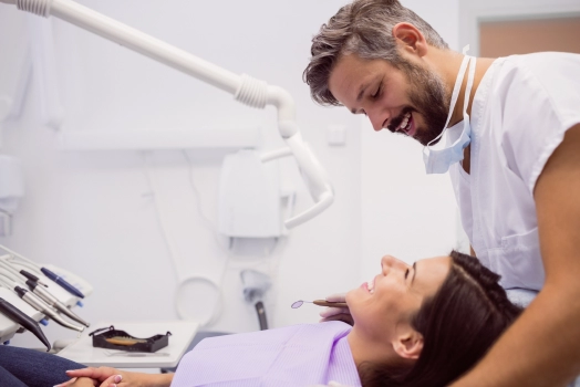 Dentist smiling while examining patient